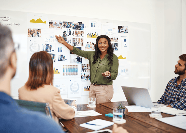 Woman presenting in a meeting with colleagues around a table.