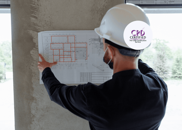 Architect in a hard hat reviews building plans, highlighting the importance of asbestos risk awareness in construction design.