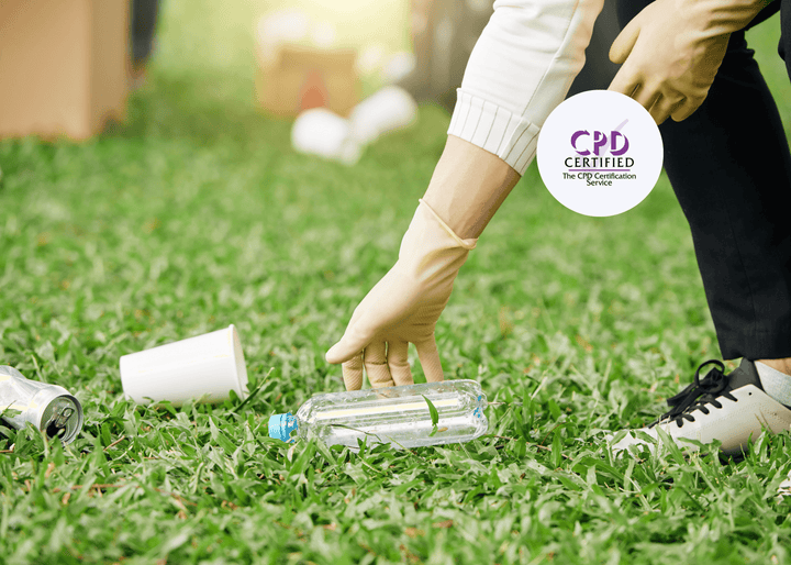 Person wearing gloves bends over to pick up a plastic bottle on grass, surrounded by leftover rubbish.