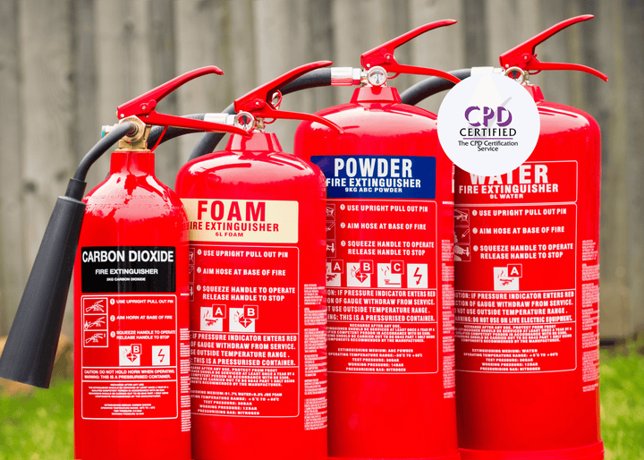 A row of red fire extinguishers—Carbon Dioxide, Foam, Powder, and Water—lined up outdoors on a grassy surface.