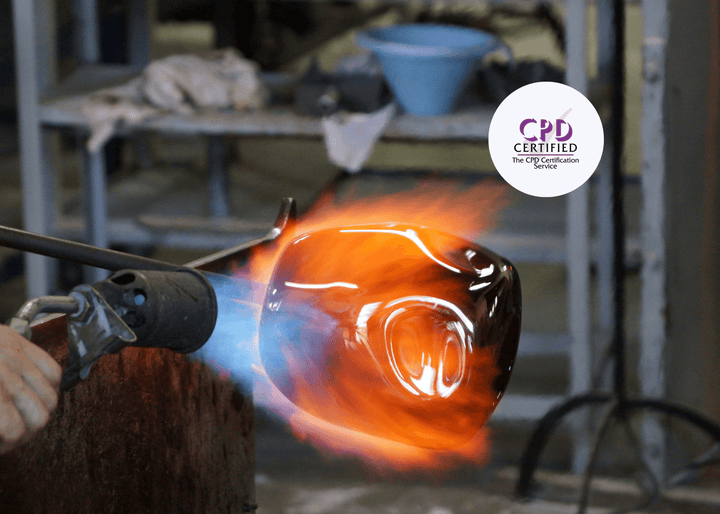 A close-up shows a hand using a gas torch to shape molten glass, with vivid orange and blue flames highlighting the hazards linked to hot works activities.