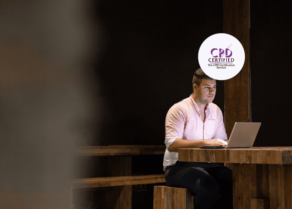 A man sits alone at his desk in a dark room, the only light coming from his laptop screen, illustrating the isolation of a lone worker.