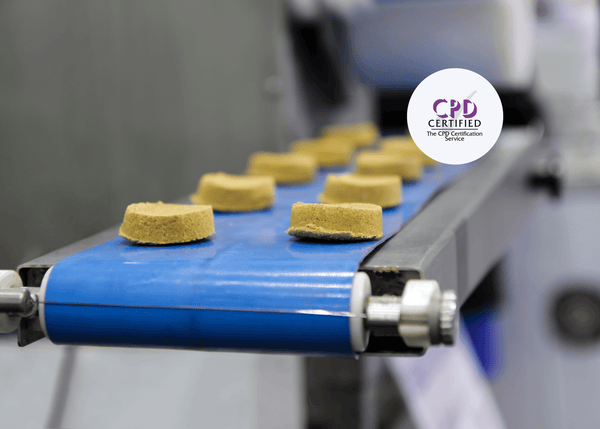Round yellow food products move along a blue conveyor belt in a manufacturing facility, representing processes covered in Level 1 Food Safety – Manufacturing training.