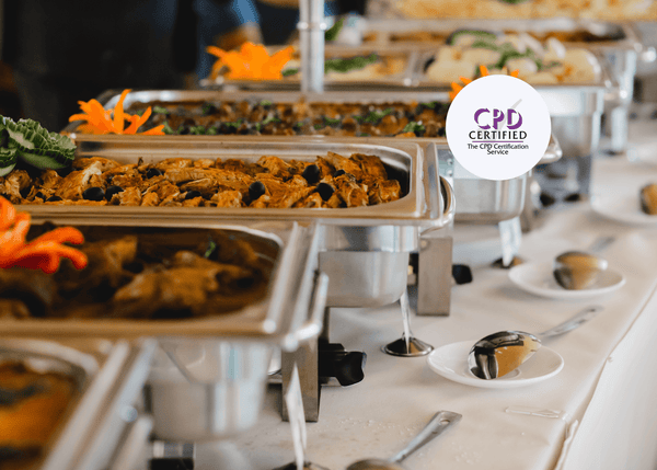 Hot buffet trays filled with a variety of foods on a catering table, symbolising safe food handling and service practices in professional catering environments.