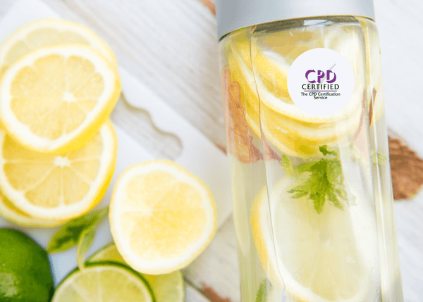 Slices of lemon and lime next to a water bottle infused with lemon, mint, and herbs, placed on a wooden surface.