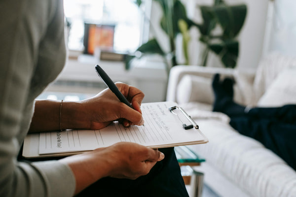 Person taking notes on a clipboard in a home setting.