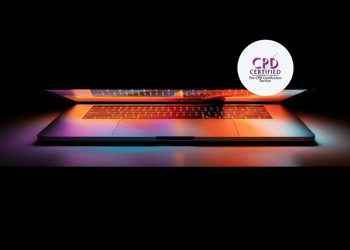A half-closed laptop glowing in the dark, casting colourful light patterns across its illuminated keyboard and screen.