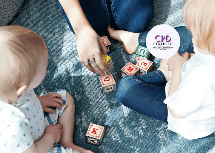 Two young children and an adult sit on a carpeted floor, playing together with colourful wooden alphabet blocks, supporting early learning and development.