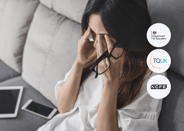 A woman sits on a sofa holding her glasses and rubbing her eyes, with a tablet and phone placed beside her, suggesting digital screen fatigue.