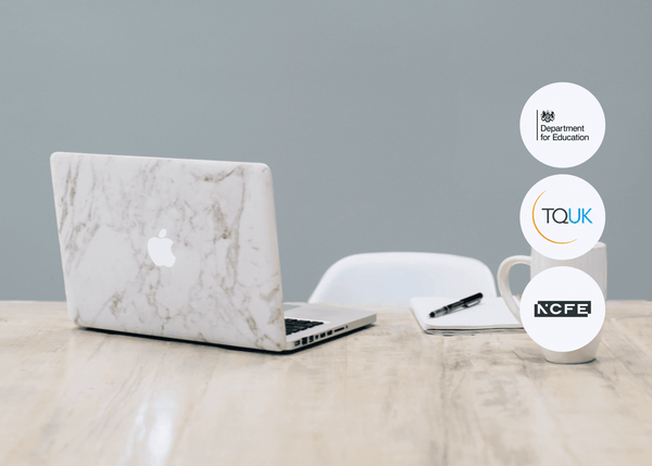 Open laptop with a marble-patterned cover on a wooden desk, beside a mug, notebook, and pen in a calm workspace setting.