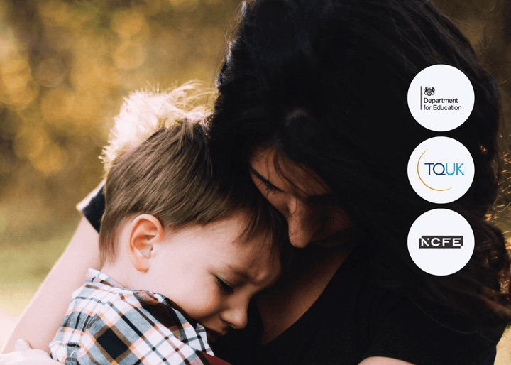 A young boy rests his head on a woman’s shoulder as she hugs him outdoors, conveying comfort, safety, and emotional support.