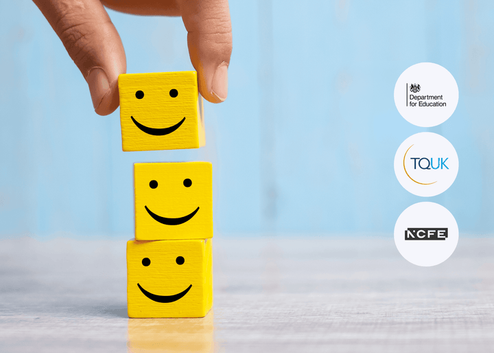 A hand places a yellow wooden block with a smiling face on top of two stacked blocks on a wooden surface, symbolising positivity and customer satisfaction.