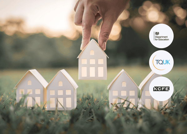 A hand lifting a small white model house from a row of identical houses on grass, with trees in the background, symbolising social housing and support.